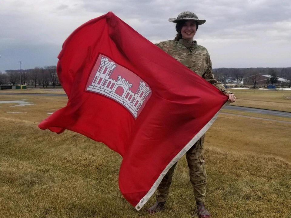 Alexis Bowering holding a flag with Fort Ontario in the background