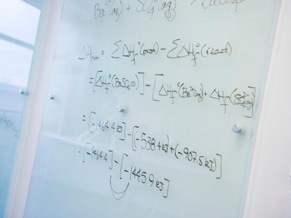 A complex math formula written on a white board