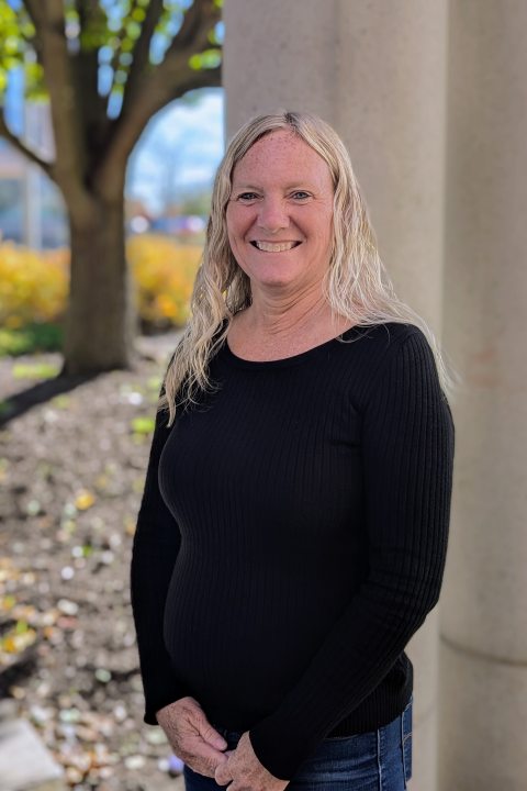 Administrative Assistant, Cindy LaDue, standing outside, smiling at the camera