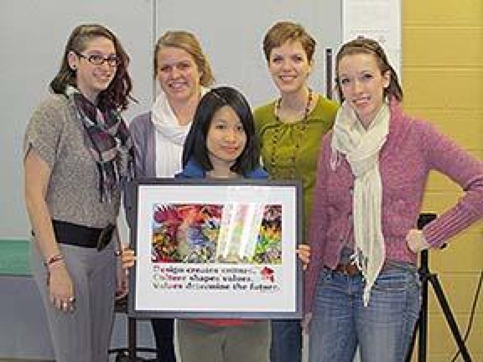 Students posing with a framed piece of artwork