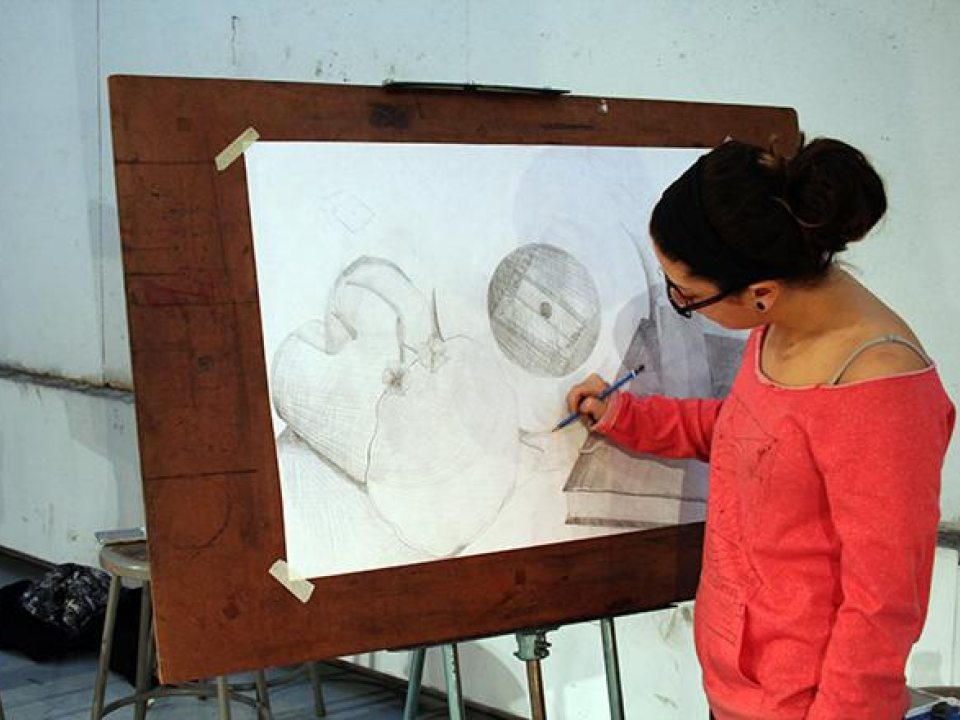 A student drawing at an easel 