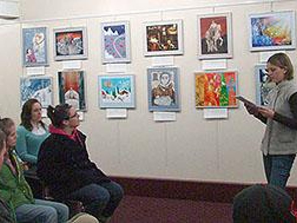 A student presenting to an audience in an art gallery