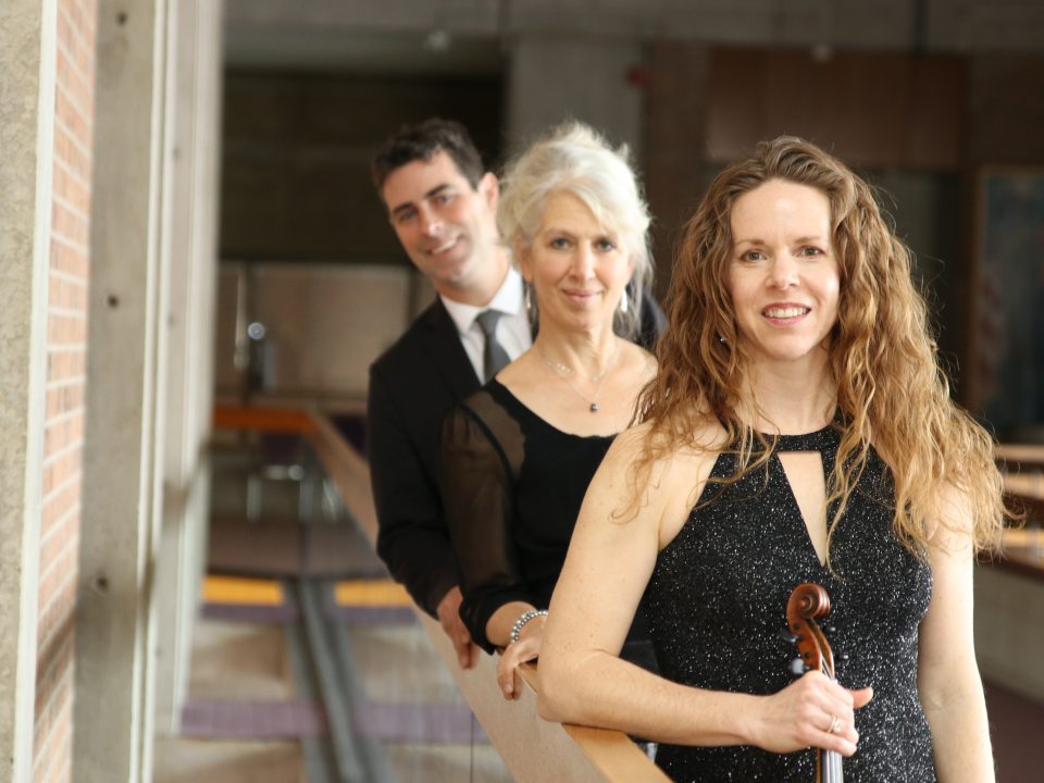 The Finger Lakes String Trio stands in a line, leaning against a railing.