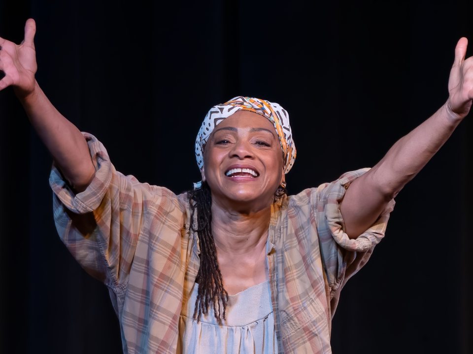 Leslie McCurdy performing with outstretched hands on stage in The Spirit of Harriet Tubman.