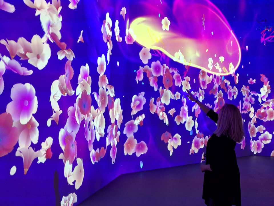 A person interacting with a colorful art installation by Lorne Covington.
