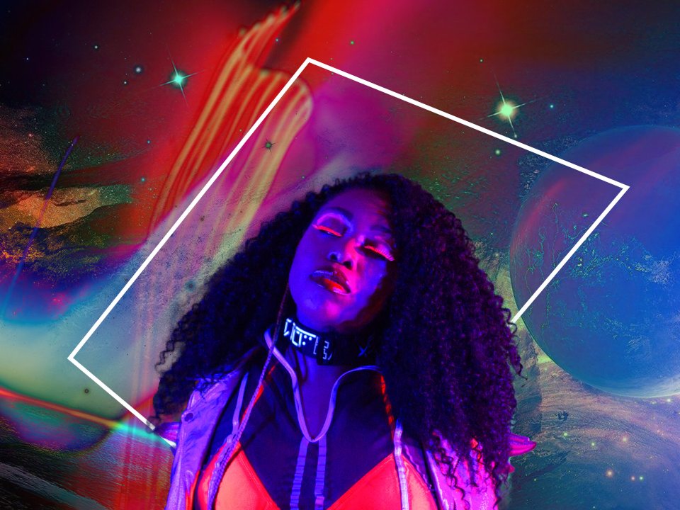 Suzi Analogue poses with her eyes closed in front of a colorful, space-inspired backdrop.