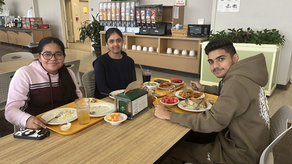 Three students sitting at a table in Cooper dining hall. 