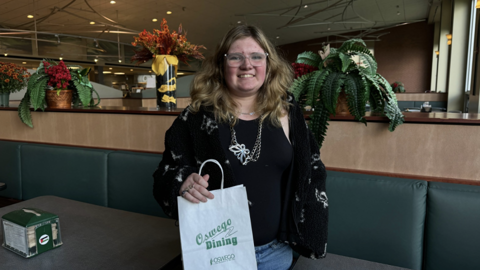 Student in Lakeside Dining Hall holding a bag for meal to go. 