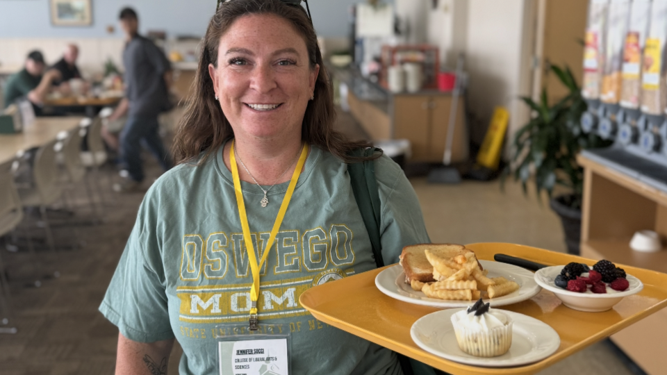 Parent wearing an Oswego shirt and holding a food tray in Cooper Dining Hall. 