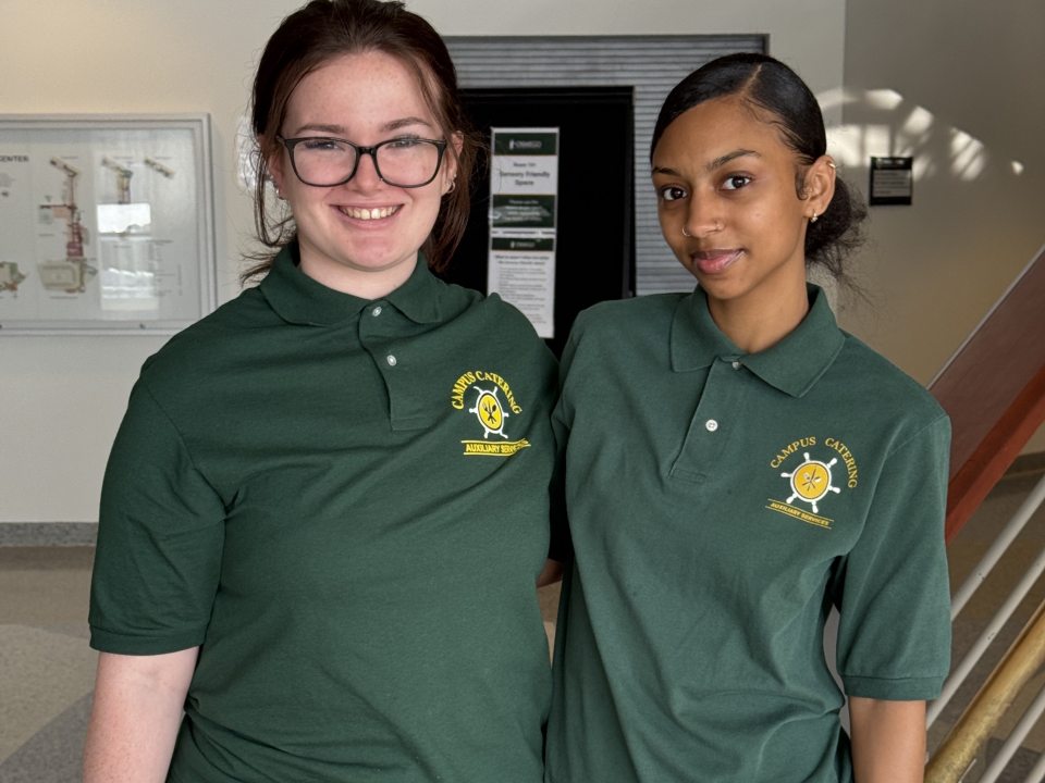 Two students working wearing their catering shirts. 