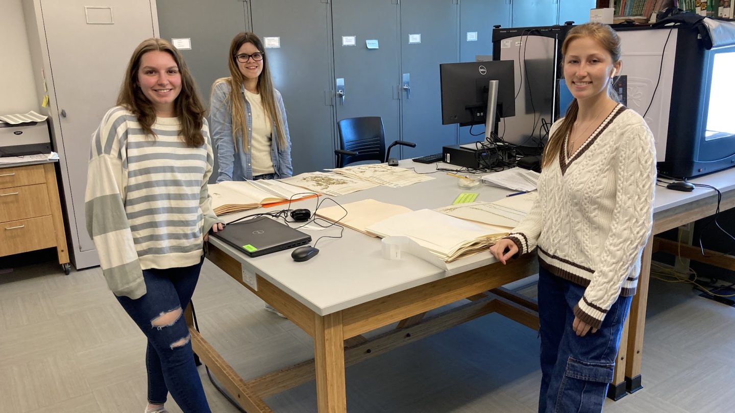 Three female students standing at a table in the lab