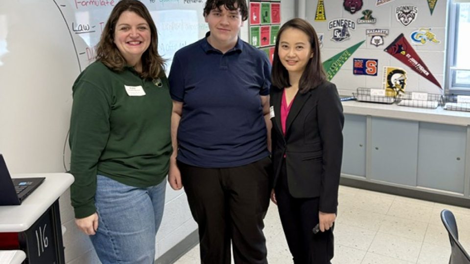 2 women and 1 man standing in a classroom in front of a whiteboard