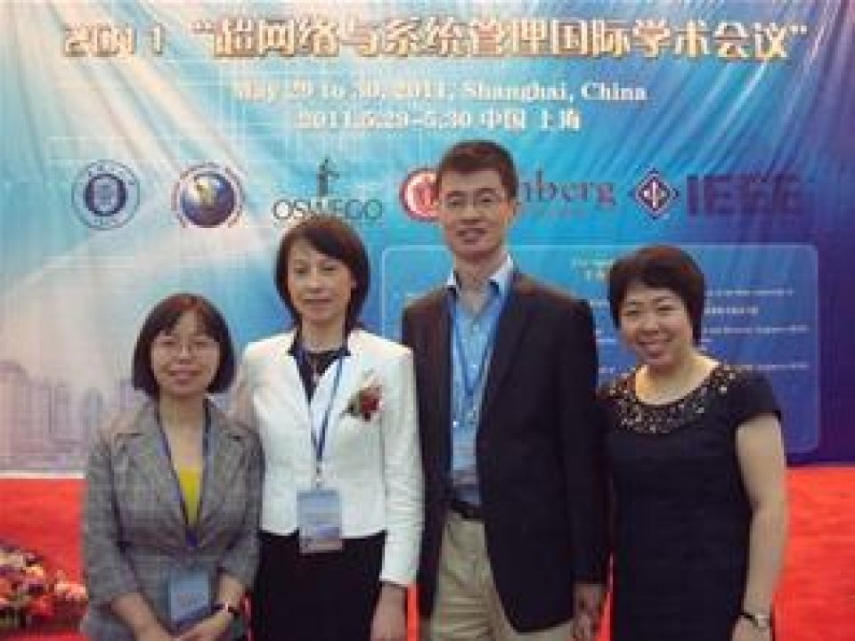 Four people posing for a photo in front of a conference banner.