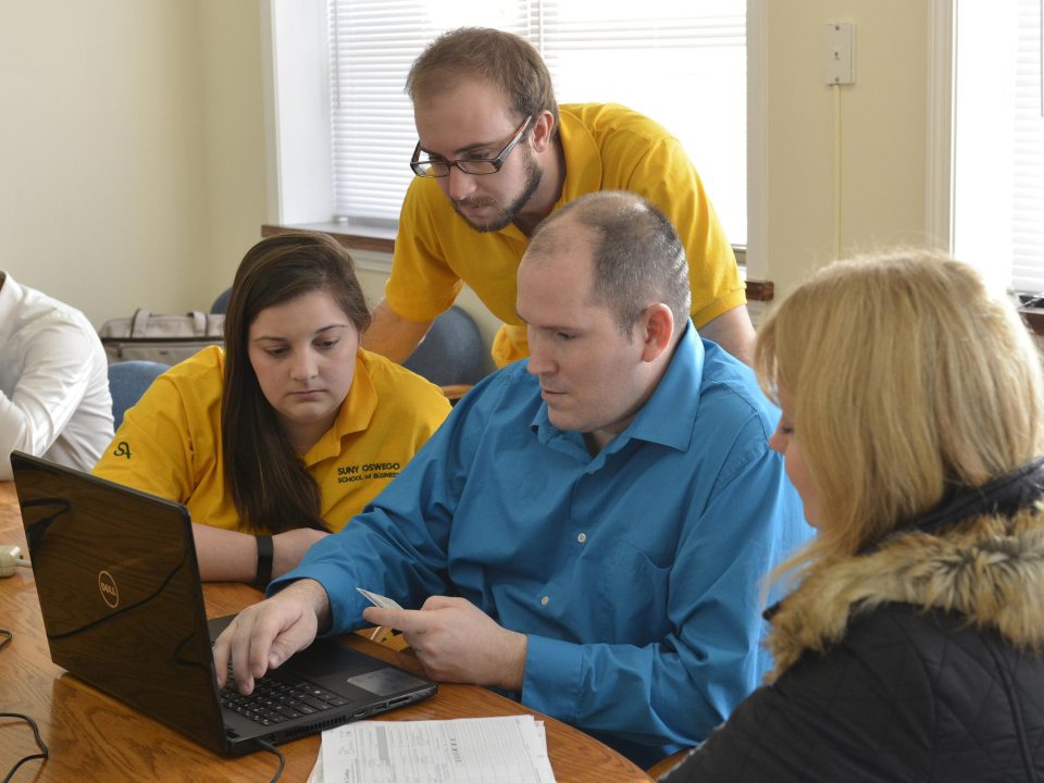 Four people looking at information on a laptop