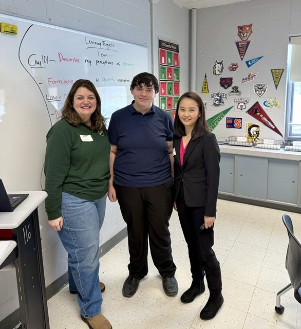 2 women and 1 man standing in a classroom in front of a whiteboard