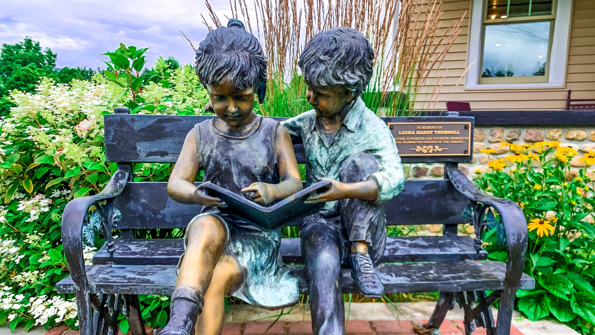 Statue of two children reading together on a bench 