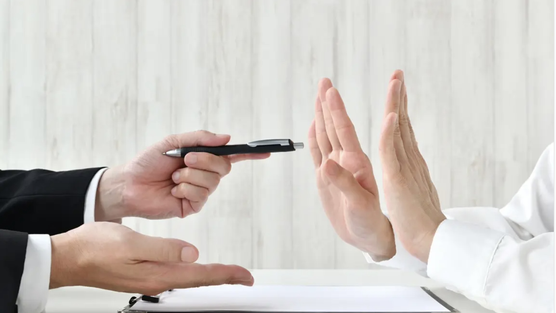 Picture of hands, 1 person forcing someone to sign and they refusing