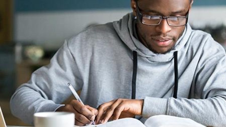 A student with a book, studying (Adobestock)