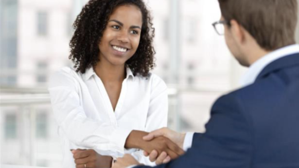 A man and woman shaking hands across a table