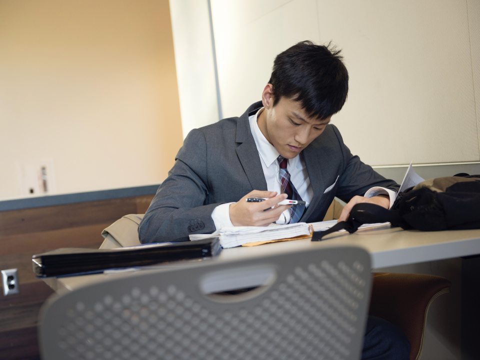 an international student at a desk, reading a textbook