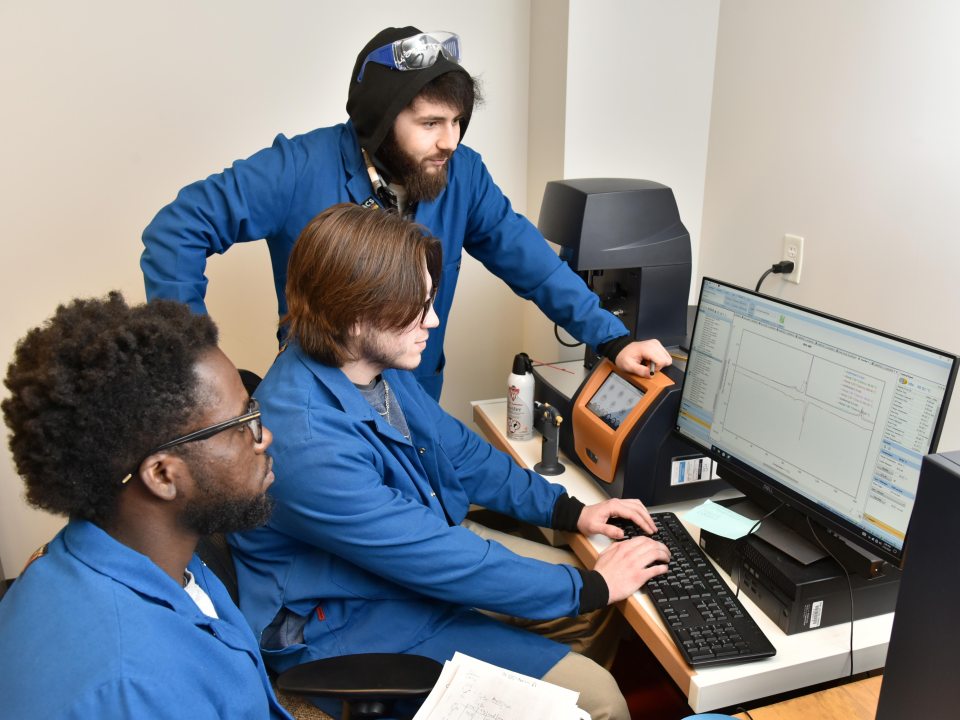 Three people looking a a lab computer