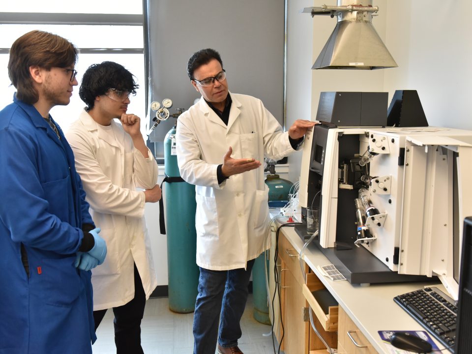 Three people looking at a piece of lab equipment