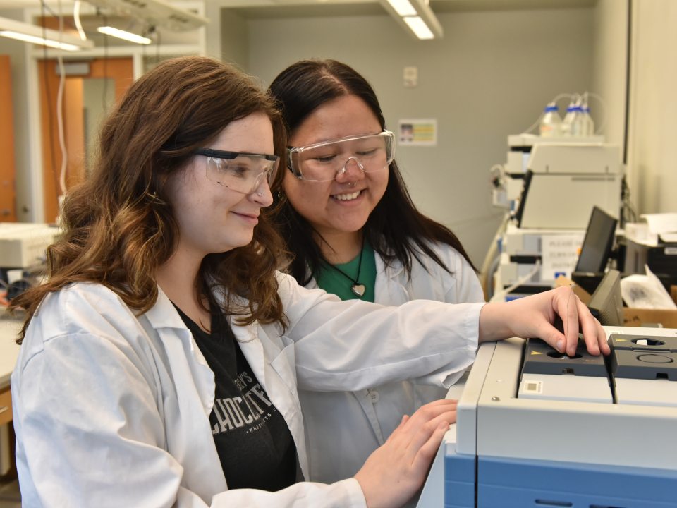 Two women working with a piece of lab equipment