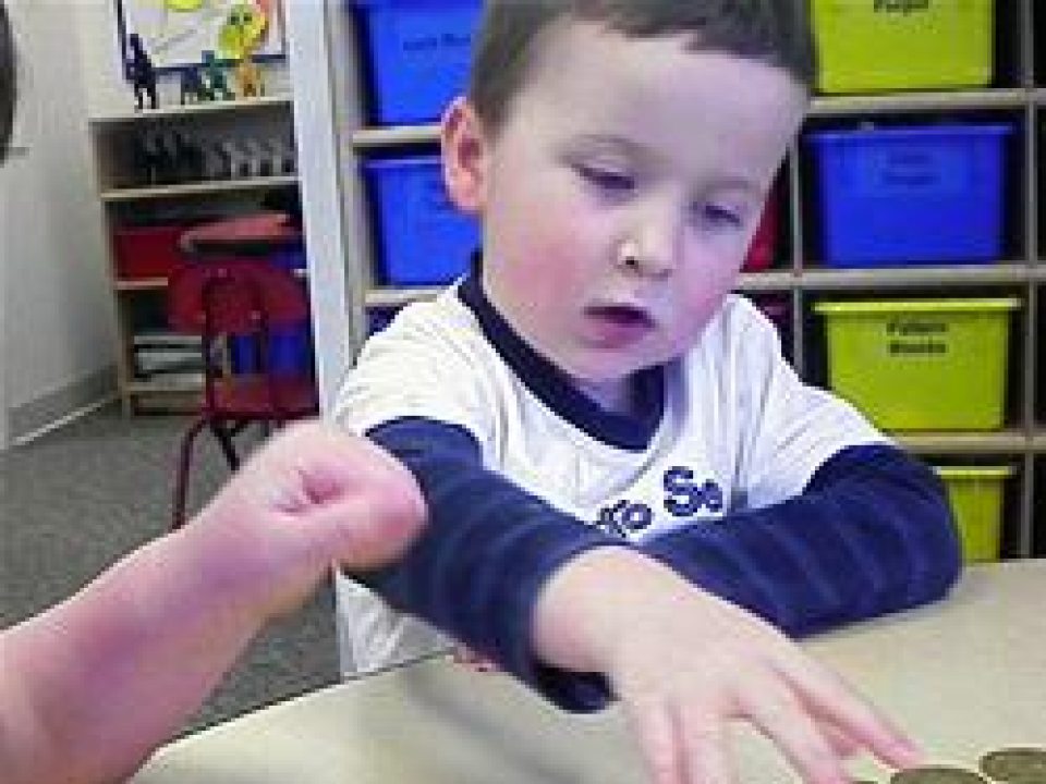 A young boy counting with coins
