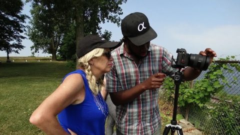 A man and a woman looking through a camera on a tripod