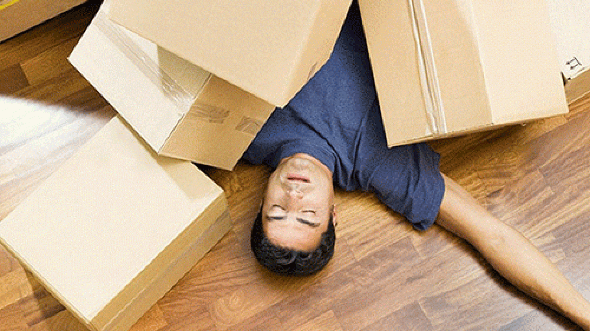 person laying under a pile of packing boxes