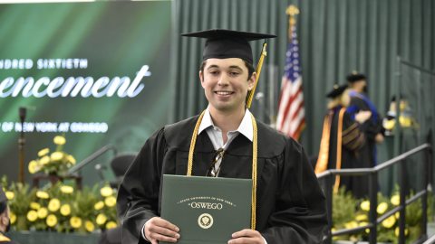 Graduate exiting the stage, holding a diploma