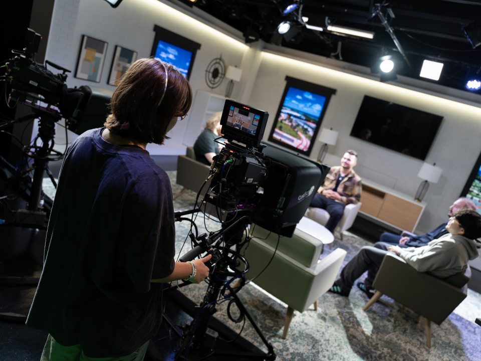 Student operating camera inside broadcast studio