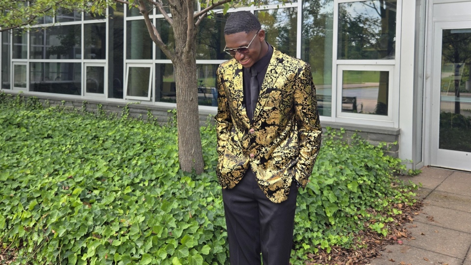 Jamal Akin-Tukur stands smiling at an awards event, dressed in formal attire, recognized as SUNY Oswego’s 2026 Outstanding Senior.