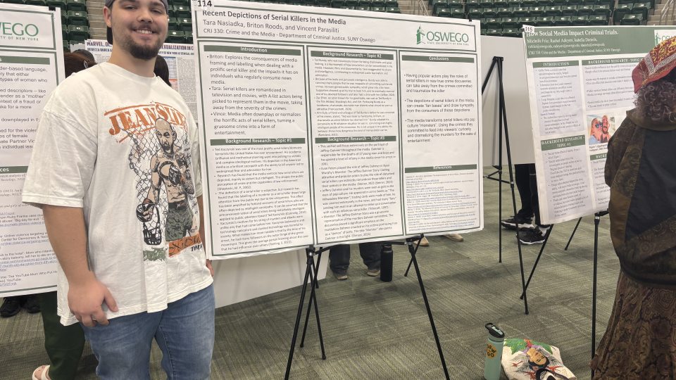 Vincent Parasiliti stands beside his SUNY Quest 2026 research poster examining recent portrayals of serial killers in television, films, documentaries, and popular media.