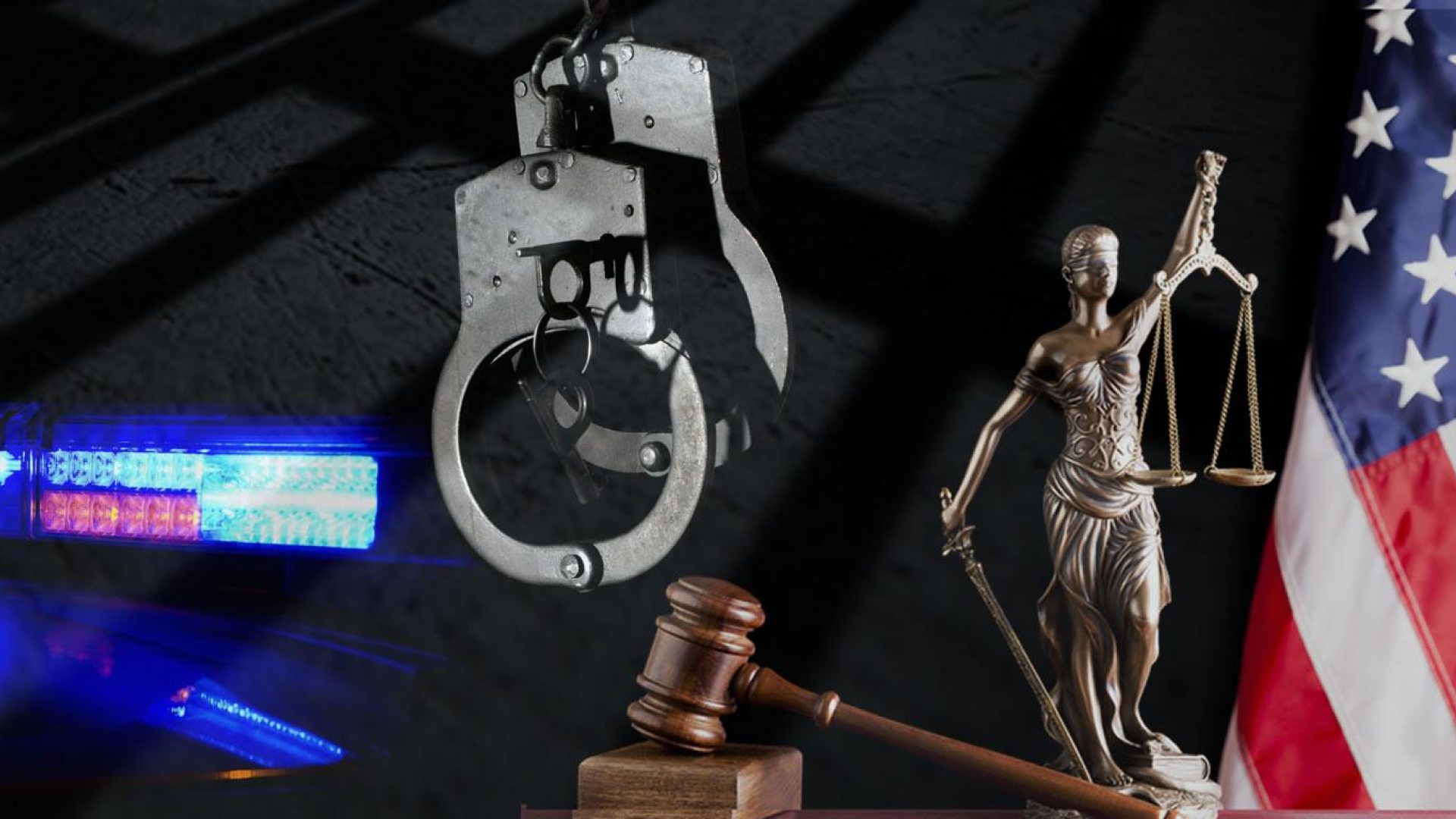 symbols of Criminal Justice: lights on a police car, handcuffs, a gavel, Lady Justice, the American flag