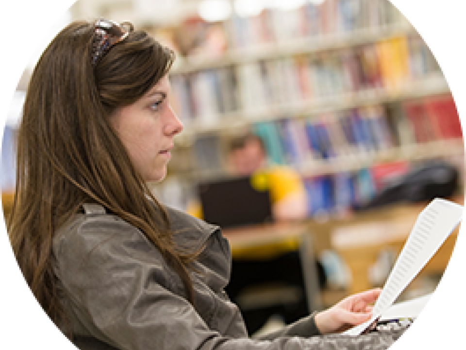 student reviewing a paper in a library