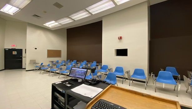 Photo of the classroom from the teacher standpoint. Showing off the podium equiptment and student chairs.