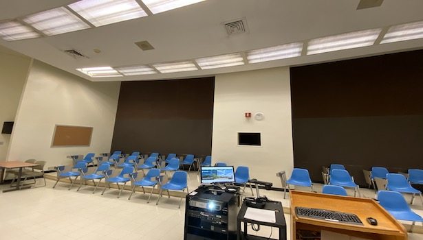 Photo of the classroom from the podium perspective. Showing the cart podium and student seats