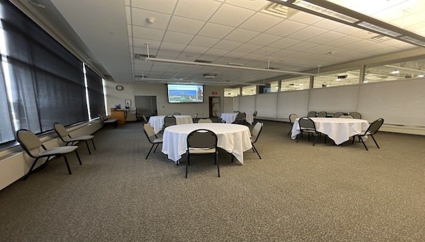 Photo shows the back of the room from the front left side. Including chairs, tables and the south projector.