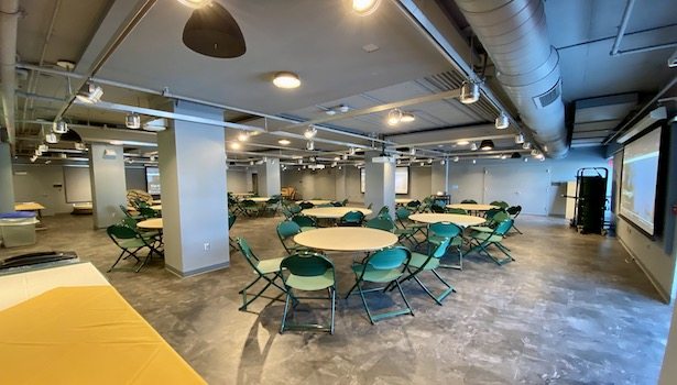 Photo shows the front of the room from the back right side showing chairs and tables.