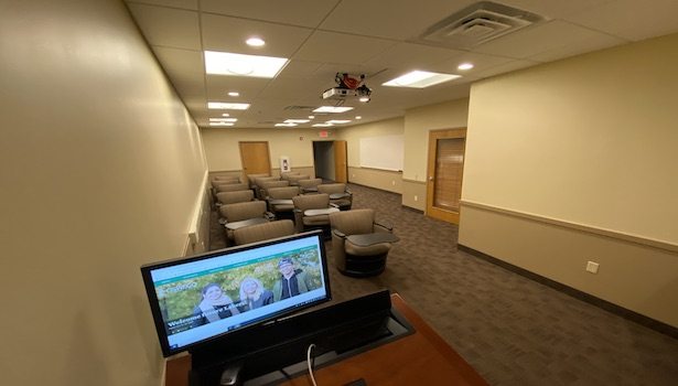 Photo of the classroom from the front podium. Showing the projector and student chairs.