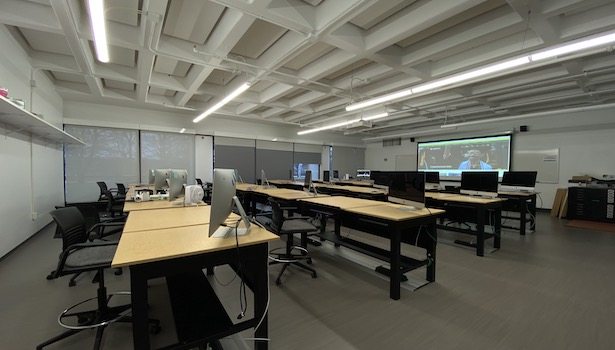 Photo shows the front of the class from the back right side. Showing student MAC's and the projector screen.