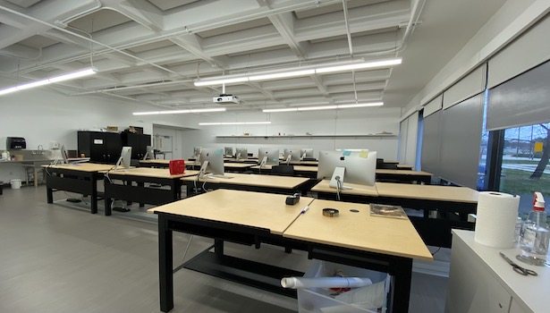 Photo of the classroomfrom the teacher standpoint. Showing the student MAC's and an extra table.