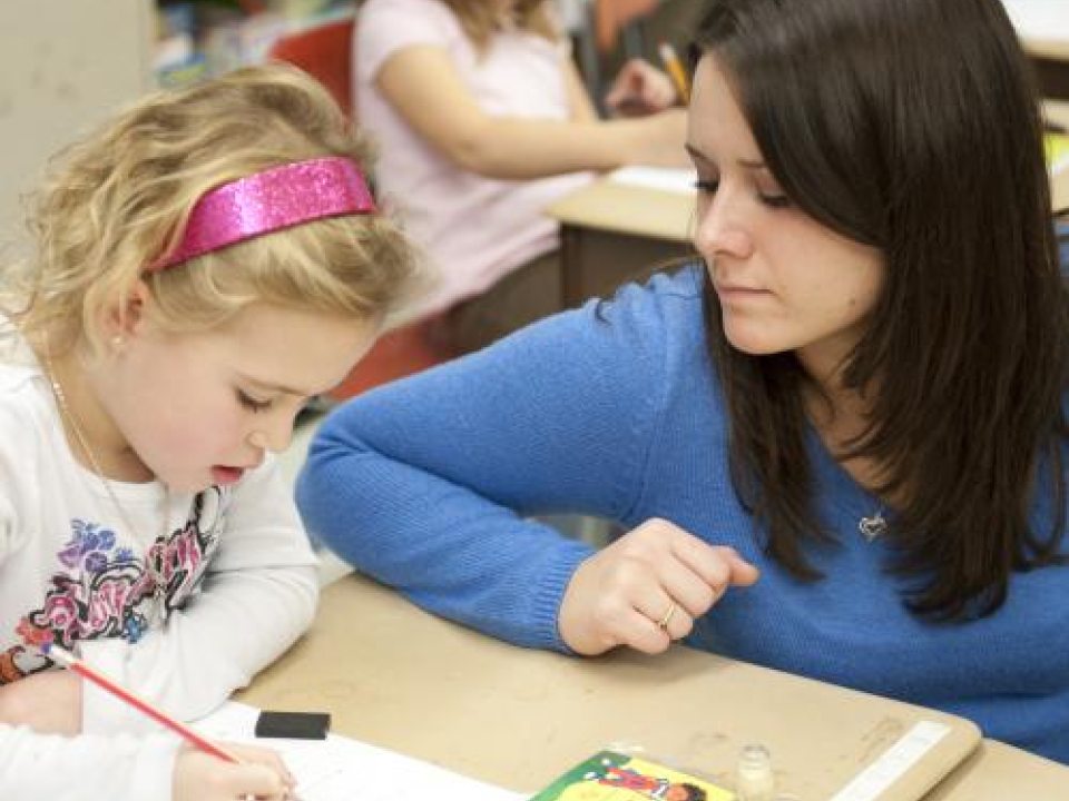 Student teacher helping elementary student with work