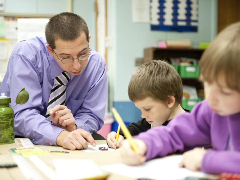 A student teacher helping young children with their work