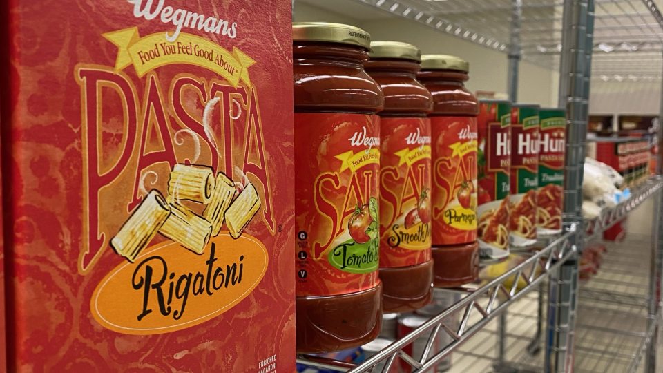 Box of pasta and jars of pasta sauce on shelf. 