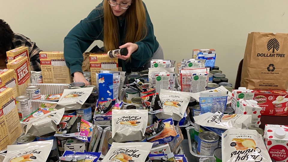 Student putting together Thanksgiving Baskets. 