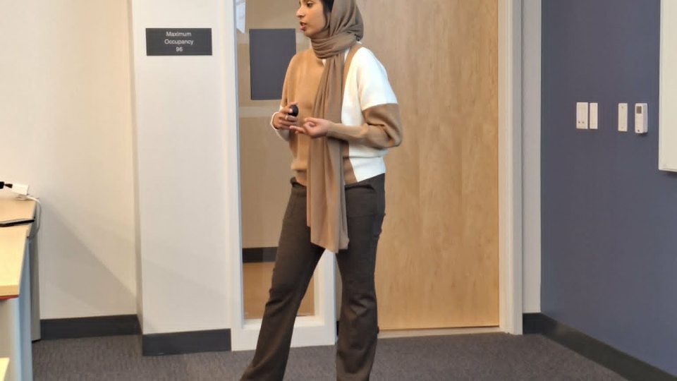GA Sumayya Sagheer stands in the front of a classroom, speaking.