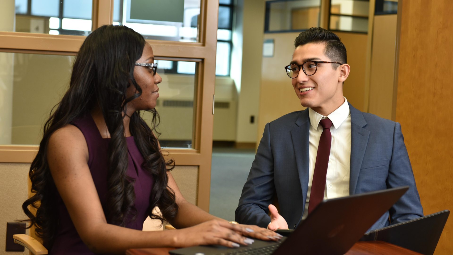 Two business students sitting at a table interacting with each other