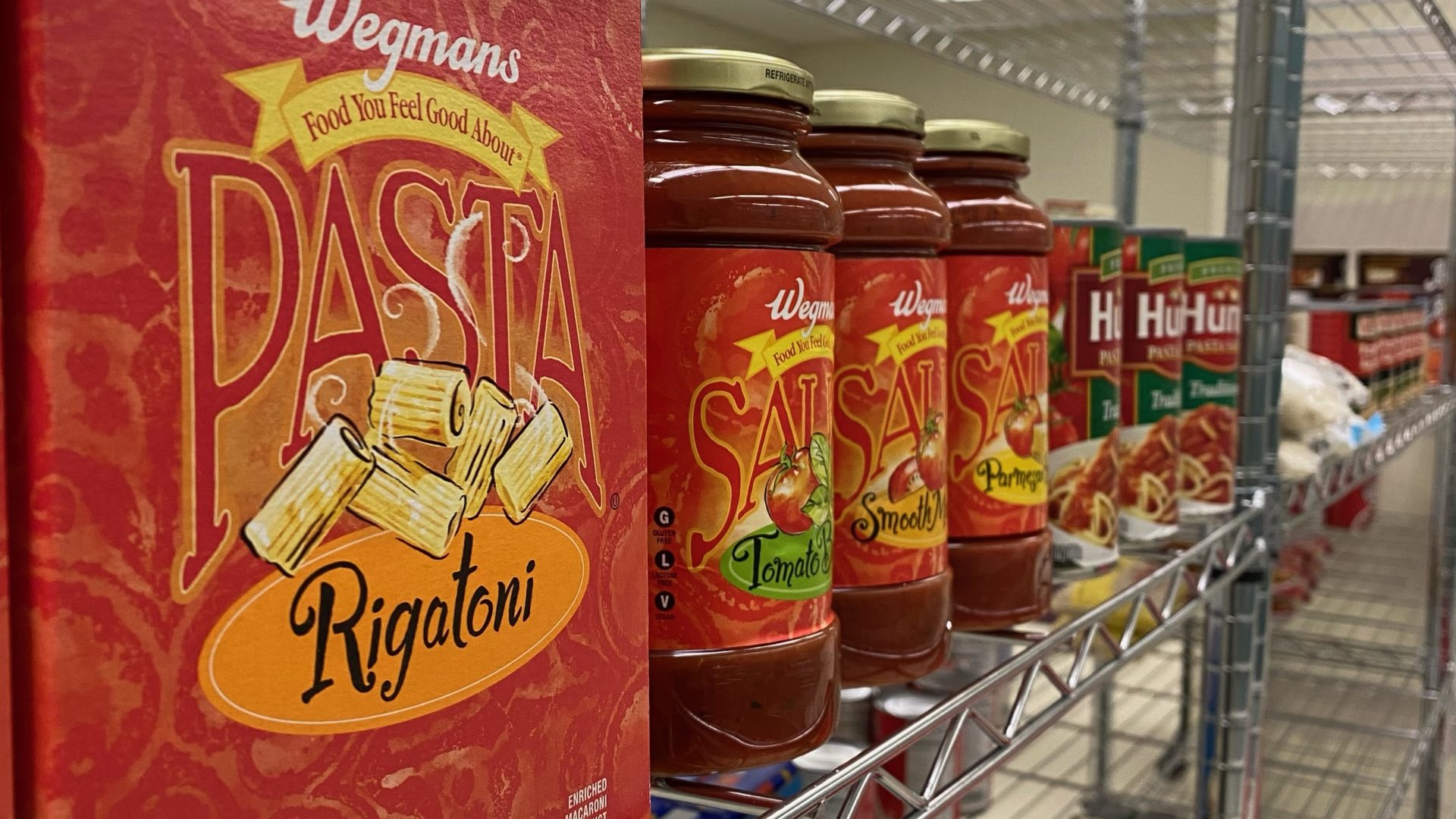 Box of pasta and jars of pasta sauce on shelf. 